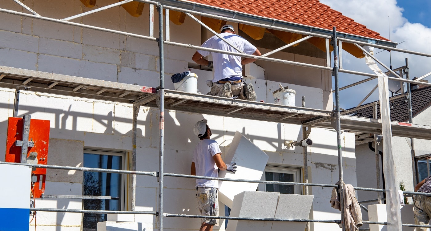 Ein Team von einer Firma für Fassadendämmung arbeitet Hand in Hand auf einer Baustelle